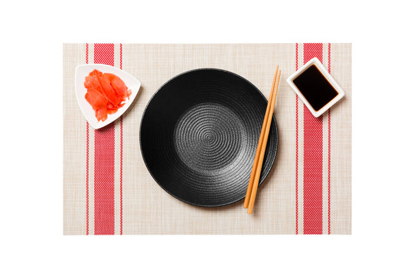 Üres kerek fekete lemez pálcika a sushi és a szójaszósz, gyömbér a sushi szőnyeg háttérben. Felülnézet másolási területtel a tervezéshez - Fotó, kép
