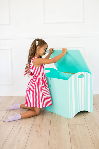 Cute girl in a beautiful dress at home plays with a decorative chest and toys - Fotoğraf, Görsel