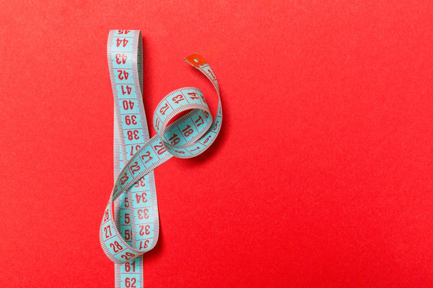 Top view of measuring tape on red background. Tailor and slim waist concept with emty space for your idea - Photo, Image