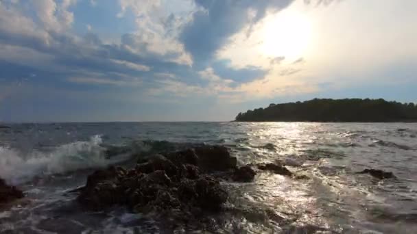 Meri-aallot kivi rannikolla vastaan sininen pilvinen taivas, aurinko ja saari vihreitä puita. Seafoam huuhtoutuminen kiviä vuoroveden aikana, roiskeet maahan turvota. Romahdus saapuvien aaltojen huuhtoutuu rantaan. Curling yli aaltojen ja takaisin luonnos aalto
 - Materiaali, video