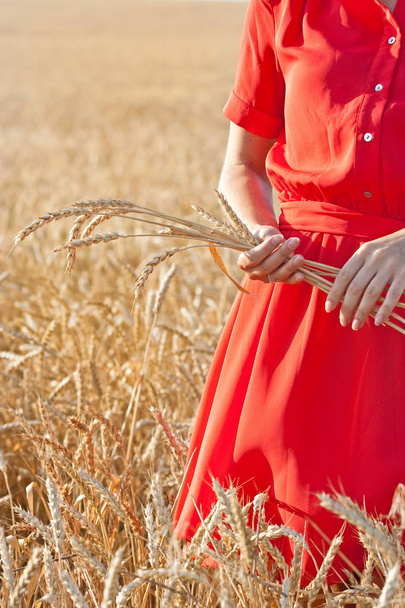 Frau im roten Kleid mit Ähren von reifem Weizen - Foto, Bild