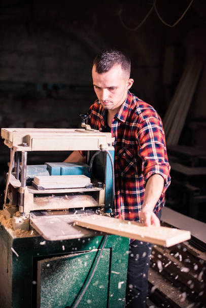 Joven carpintero guapo trabajando con madera en su taller de carpintería
 - Foto, Imagen