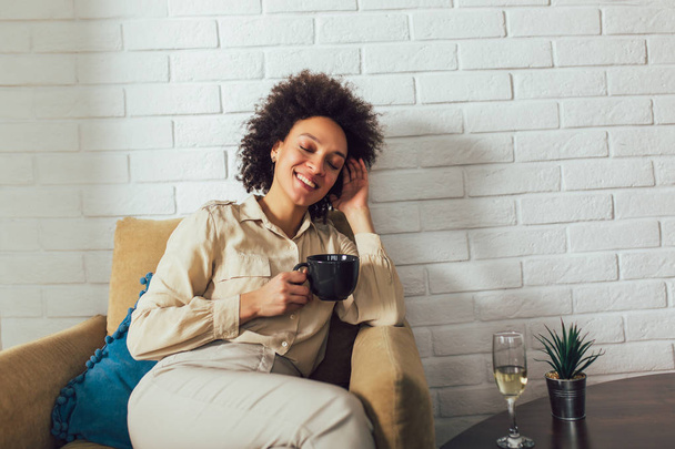 African American woman in her living room drinking holding a cof - Photo, Image