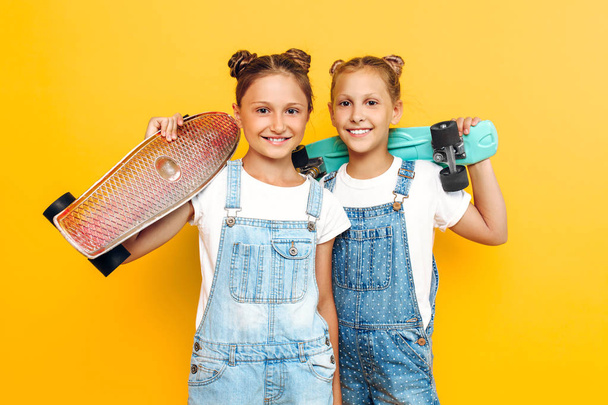 Two teenagers, stylish children posing with skateboards in their - Foto, afbeelding