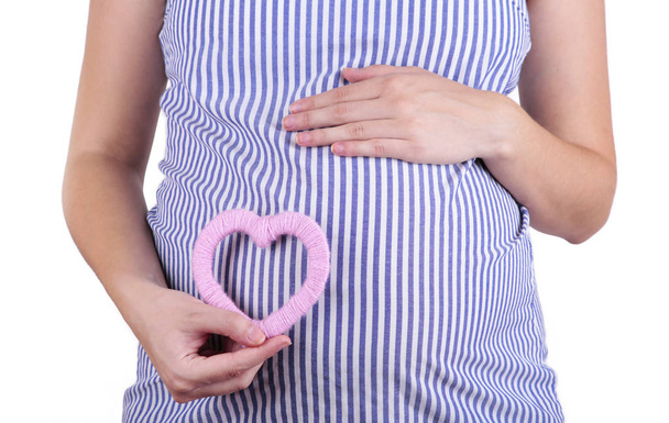 白い背景に隔離された腹に置かれたピンクのハートのシンボルを持つ妊娠中の女性 - 写真・画像