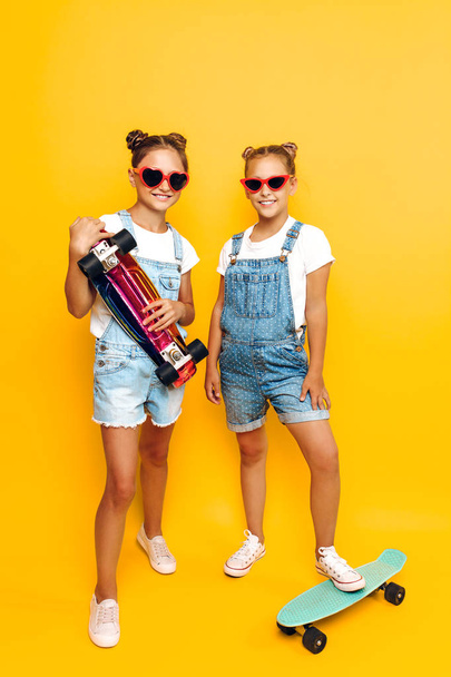 Two teenagers, stylish children posing with skateboards in their - Foto, Imagen