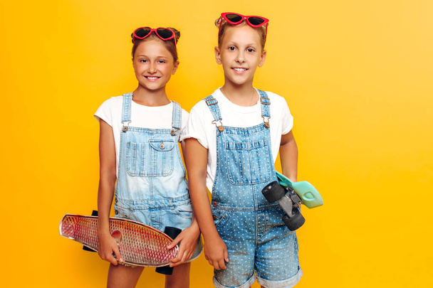 Two teenagers, stylish children posing with skateboards in their - Zdjęcie, obraz