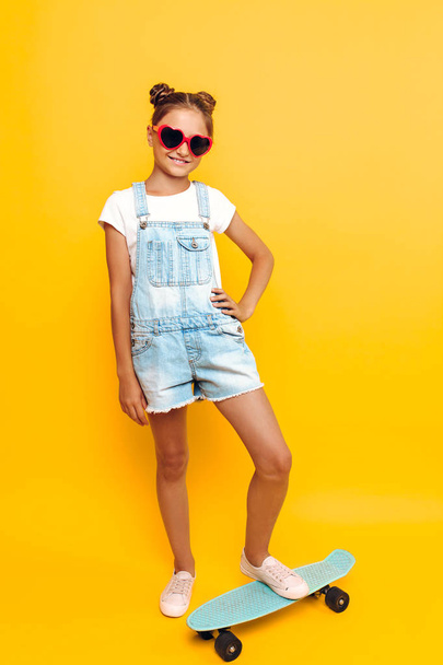 Happy teenager with skateboard, stylish girl posing on yellow ba - Φωτογραφία, εικόνα