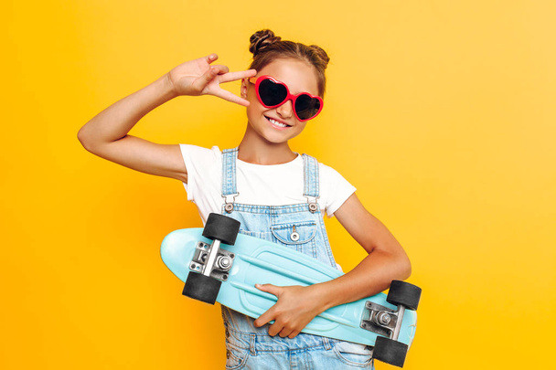 Happy teenager with skateboard, stylish girl posing in sunglasse - Valokuva, kuva