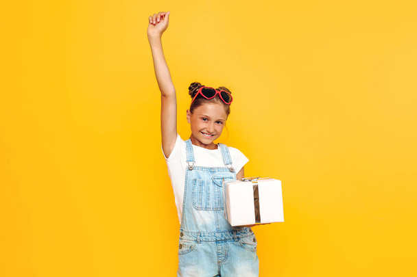 Shocked young girl, a teenager holds a gift box in hand, standin - Foto, afbeelding