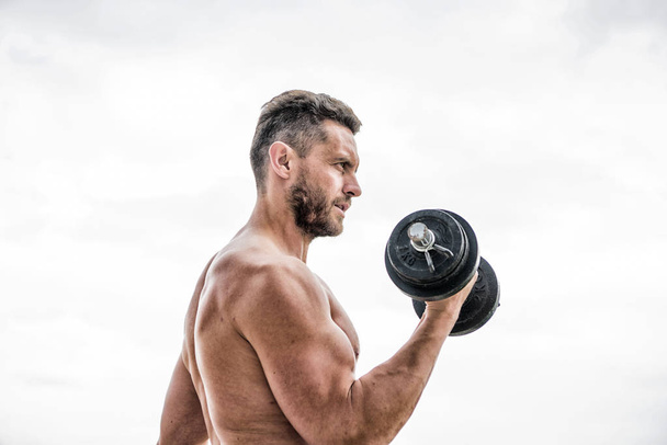athletic body. Dumbbell gym. Muscular man exercising in morning with barbell. fitness and sport equipment. success. Perfect biceps. man sportsman weightlifting. steroids. Getting into the groove - Foto, Bild