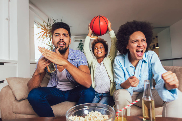 Gelukkige Afro-Amerikaanse familie van drie kijken tv en juichen  - Foto, afbeelding