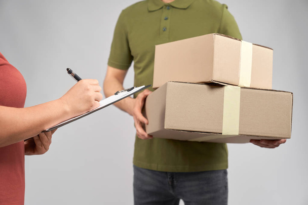 Delivery man holding two boxes, client signing receipt. - Fotó, kép