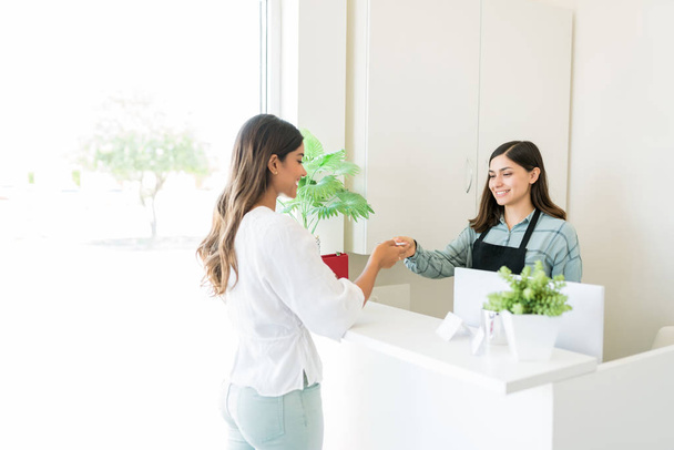 Client femme donnant carte de crédit à la réceptionniste après traitement au salon
 - Photo, image