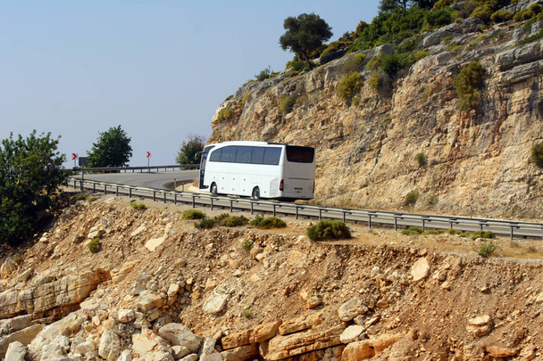 Белый автобус движется по горной дороге вдоль Средиземного моря. Концепция поездки на автобусе
. - Фото, изображение