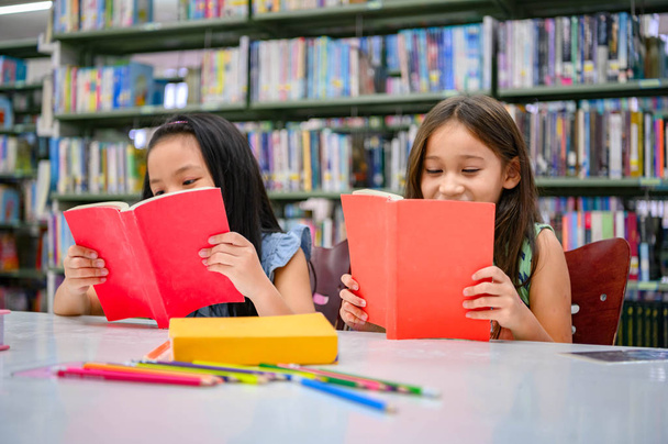 Onnellisuus kaksi söpöä monimuotoisuutta tytöt lukeminen kirja koulussa librar
 - Valokuva, kuva