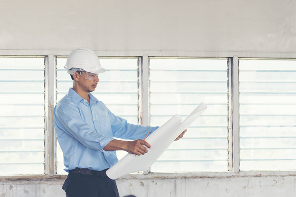 Ingeniero de Éxito usa casco blanco para verificar la seguridad y los planos de construcción impresión azul. Concepto de construcción
. - Foto, imagen