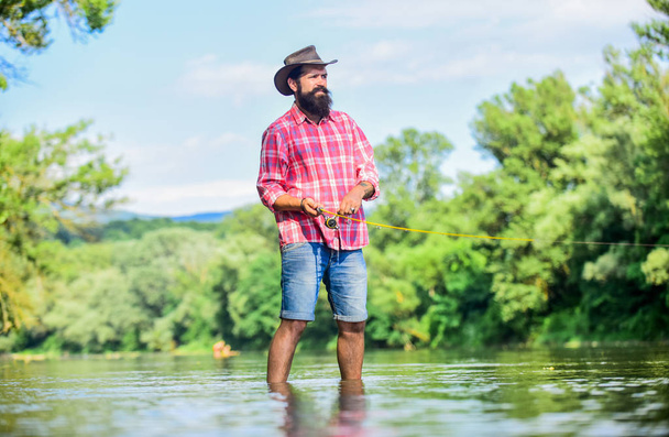 Fisherman fishing equipment. Hobby sport activity. Calm and peaceful mood. Fisherman alone stand in river water. Some kind meditation. Fish normally caught in wild. Trout farm. Man bearded fisherman - Foto, immagini