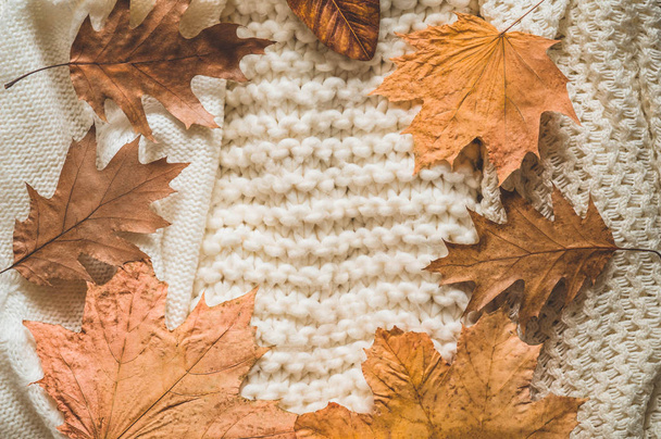 Fall Background with warm sweaters. Pile of knitted clothes with autumn leaves, warm background, knitwear, space for text - Foto, afbeelding