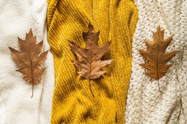 Fall Background with warm sweaters. Pile of knitted clothes with autumn leaves, warm background, knitwear, space for text - Photo, Image