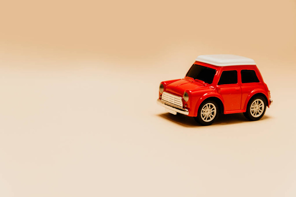 Speelgoed rode auto op een beige effen achtergrond met plaats voor tekst - Foto, afbeelding