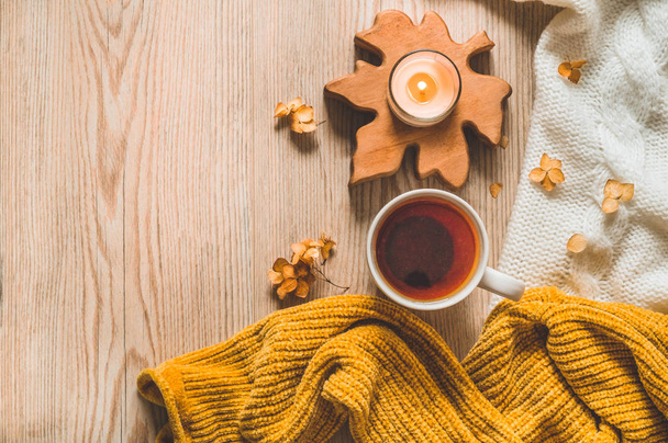 Fondo con suéteres calientes y té taza. Bodegón acogedor en tonos cálidos, espacio para el texto, concepto de otoño invierno
. - Foto, imagen