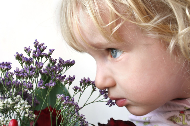 Little girl smelling flowers - Foto, immagini