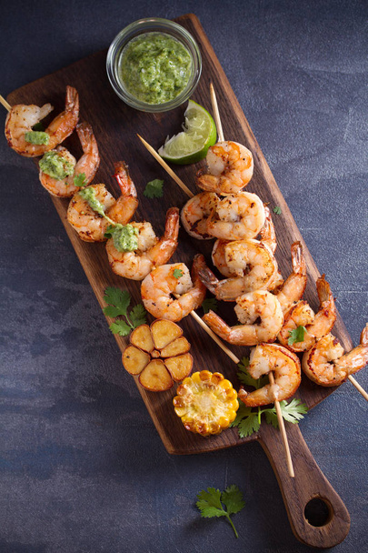 Skewered shrimps with garlic butter sauce served with cilantro and lime on serving board - Zdjęcie, obraz