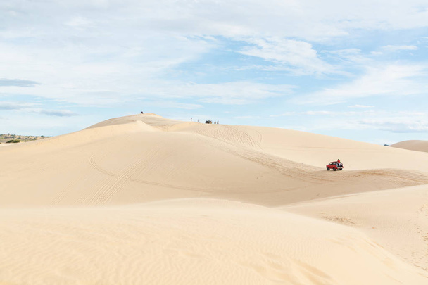 Mui Ne, Vietnam - June 2019: off-road car driving through desert sand dunes at sunrise - Photo, Image