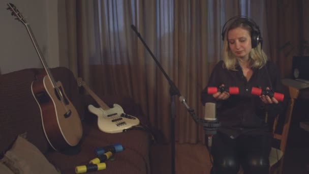 Home Recording Studio. Een vrouw registreert het geluid van shakers met behulp van een microfoon in een computer. - Video