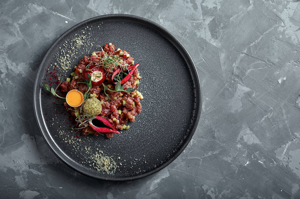 Beef tartare with egg yolk on a gray surface, top view, close-up copy space - Photo, Image