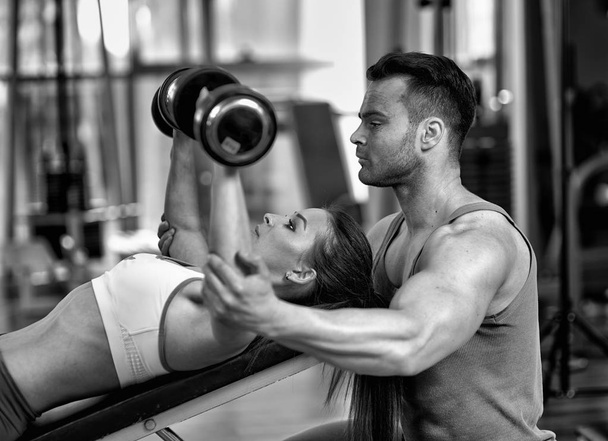 Personal trainer helping woman working with dumbbells - Фото, зображення
