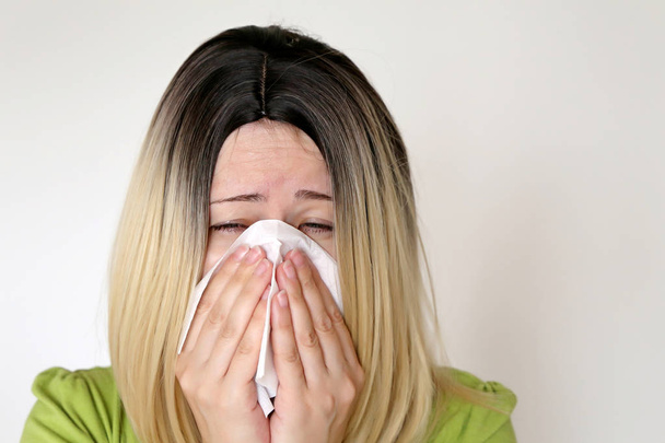 Хвора жінка чхає і дме носом у носовичку. Концепція застуди та грипу, нежить, повітряна інфекція
 - Фото, зображення