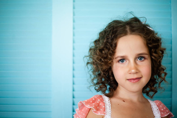 Portrait of a little girl on a blue background in a pink nightgown. - Photo, Image