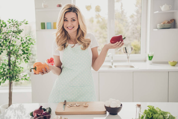 Portrait of her she nice attractive lovely charming pretty cheerful cheery wavy-haired lady making homemade dinner holding on palms vegs choose choice in light white interior kitchen - Zdjęcie, obraz