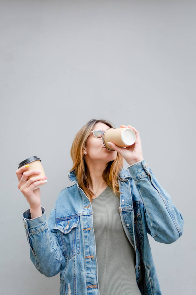 Blonde girl with paper cups of coffee on grey - Φωτογραφία, εικόνα