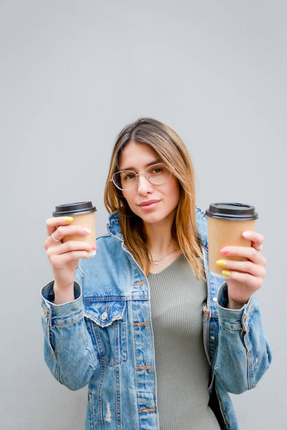 Blonde girl with paper cups of coffee on grey - Fotoğraf, Görsel