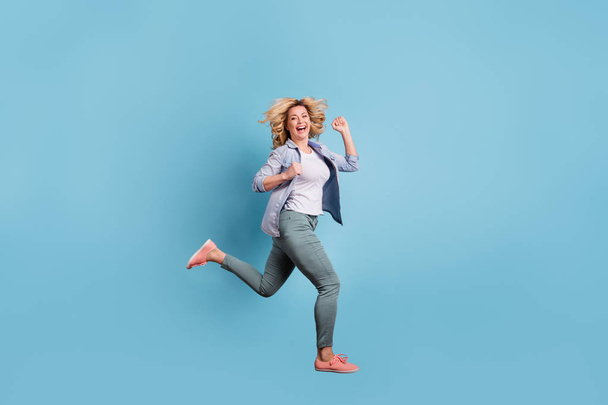 Full size profile side photo of nice lady running laughing wearing pants trousers isolate dover blue background - Фото, зображення