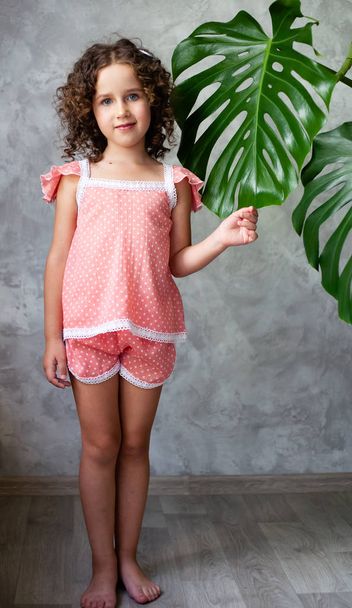 Little girl model with monstera. Portrait of a little girl with monstera leaves. - Фото, изображение