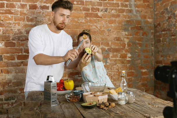Young couple cooking and recording live video for vlog and social media - 写真・画像