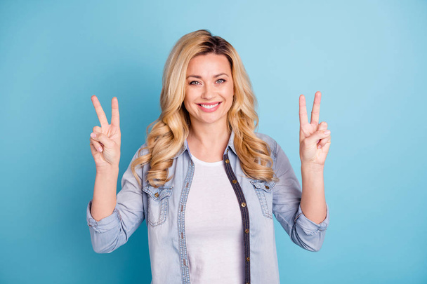 Portrait of lovely person making v-signs looking at camera isolated over blue background - Foto, Imagen