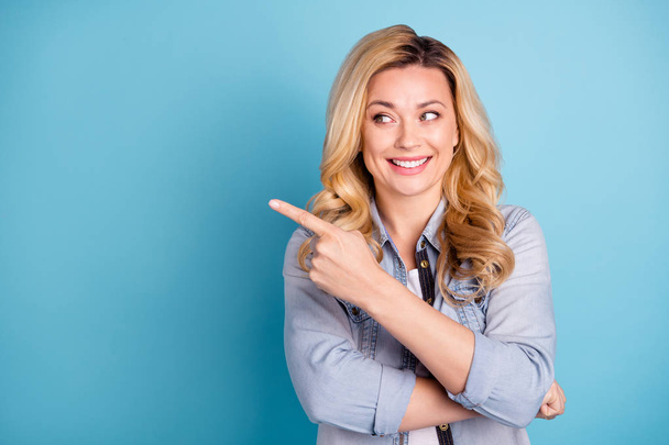 Close up photo of cheerful woman pointing at copy space showing ads isolated over blue background - Foto, afbeelding