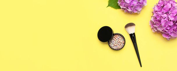 Set von dekorativen Kosmetik-Make-up-Pinseln, Rouge-Gesichtskugeln, rosa Hortensienblüten auf gelbem Hintergrund Draufsicht flach legen Kopierraum. Beauty-Blogger-Konzept. Mode-Hintergrund. Make-up Zubehör - Foto, Bild
