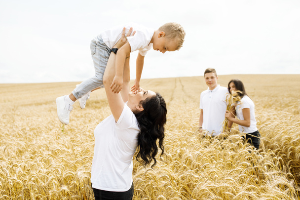 Happy family - brothers, sister and mom have fun on the wheat field. Summer vacation time - Photo, Image