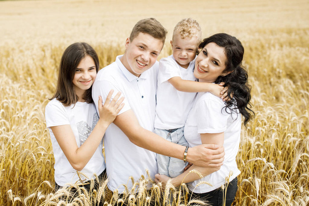 Οι ευτυχισμένοι οικογενειακοί αδελφοί, η αδελφή και η μαμά διασκεδάζουν στο χωράφι με το σιτάρι. Θερινή ώρα διακοπών - Φωτογραφία, εικόνα