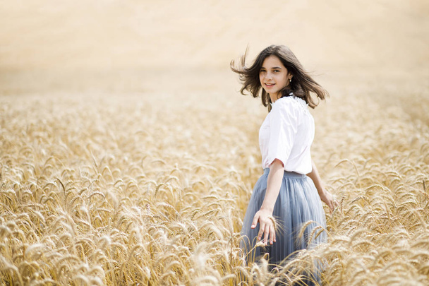 Beauty Girl Al aire libre disfrutando de la naturaleza. Hermosa adolescente modelo chica corriendo en el campo de trigo, luz del sol
. - Foto, imagen