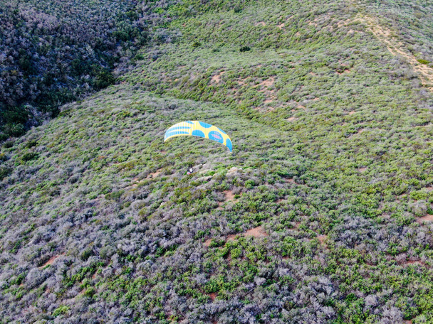 Para-vitorlázó át a tetejét a hegyek nyári napsütéses napon. Para-vitorlázó a para-sík, strops-szárnyaló repülési pillanatban repül át Black Mountain San Diego, Kalifornia. Usa.  - Fotó, kép