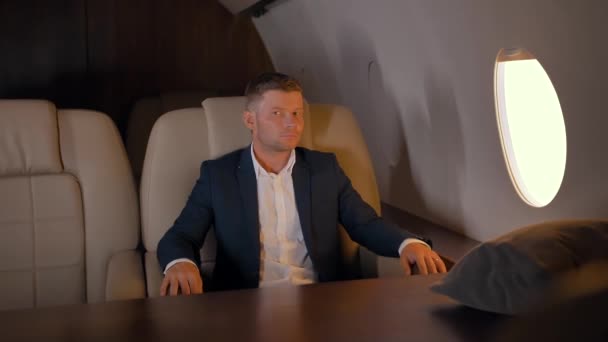 Portrait of entrepreneur sitting in comfortable business jet armchair - Footage, Video