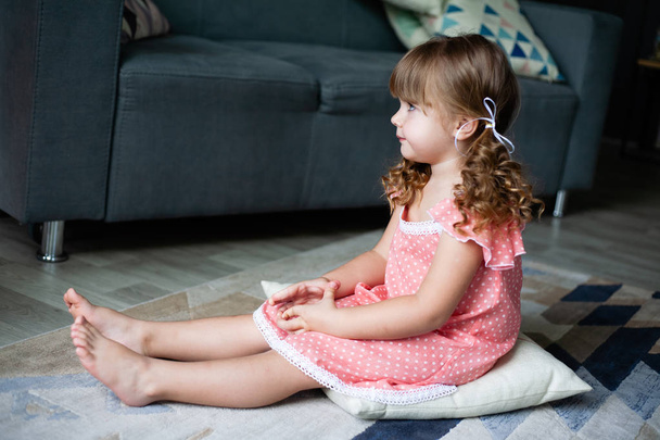 Little girl sitting pillow on the floor. In a nightgown. - Foto, Bild