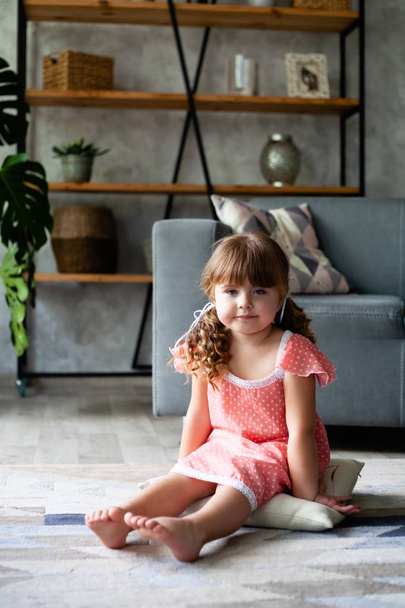 Little girl sitting pillow on the floor. In a nightgown. - Photo, Image